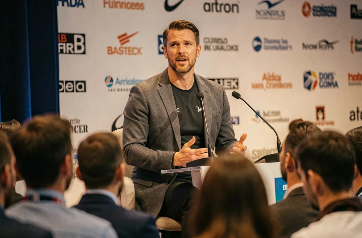 Entrepreneur sportif prenant la parole lors d'une conférence sur l'innovation et le sport connecté devant un public attentif